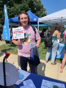 Person holds up a paper fan that reads "I am a voting fan."