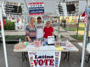Photo of three adults standing behind a voter information table.